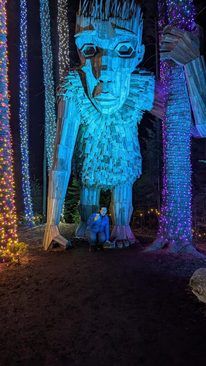 Hadley Blodgett 26 poses with a giant wooden troll at the Costal Maine Botanical Gardens in Boothbay, Maine.