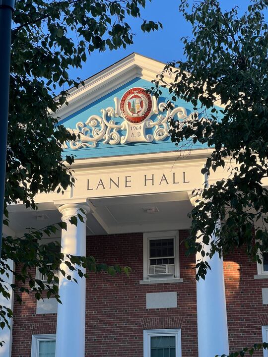 Lane Hall, the college administrative building where the Bates financial offices are, illuminated by the sun on Alumni Walk.