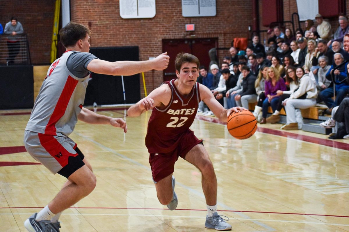 Peter Psyhogeos '26 dribbling around the Wesleyan defender and is going in for a layup.