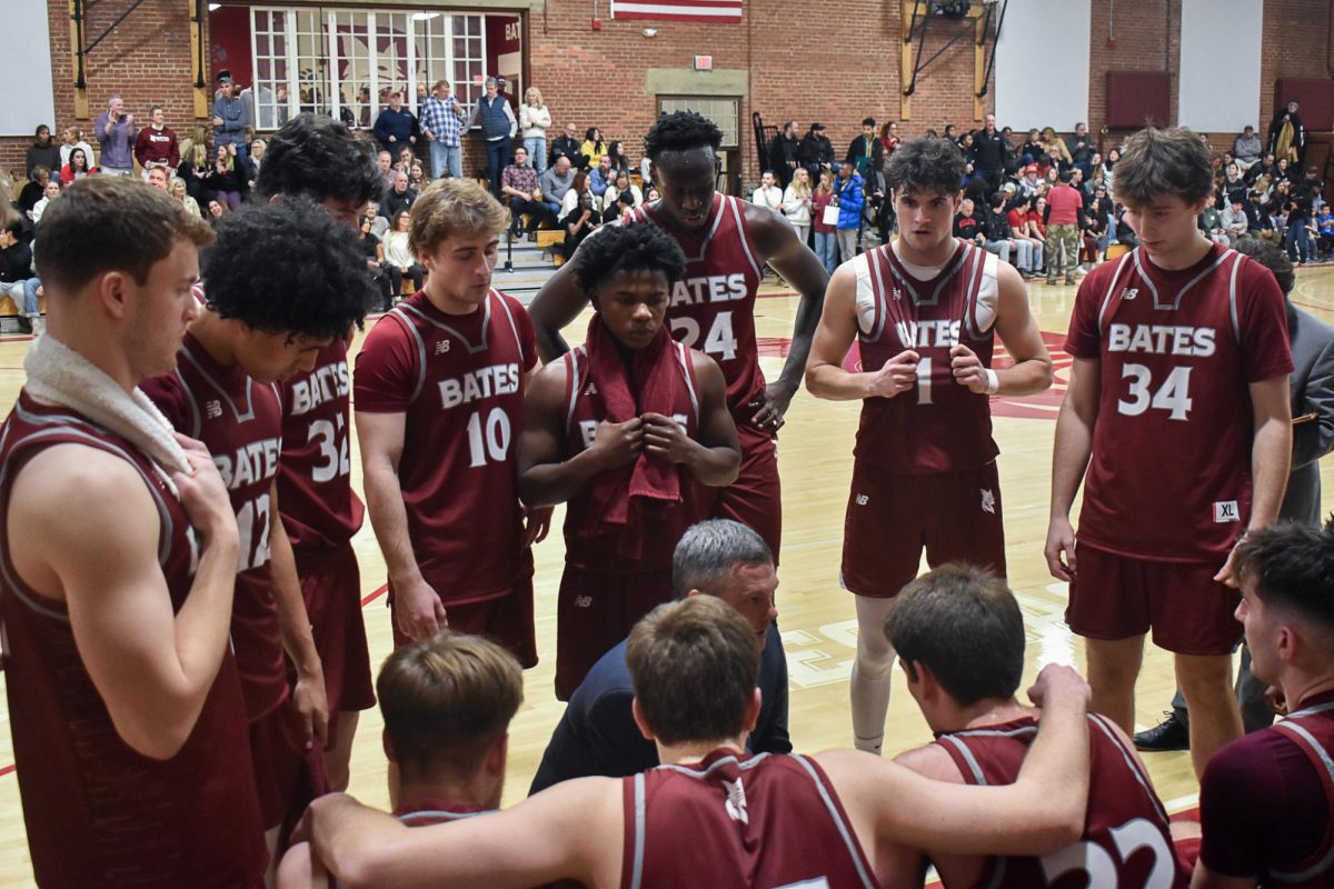 The Bates Men's Basketball Team huddling during a timeout in the midst of a close game.