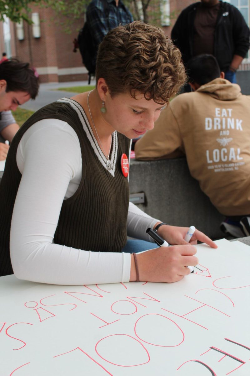 Jamie Shelton, Class of '27, creates a sign at the Students Demand Action walkout near Commons on Friday, September 5th. 