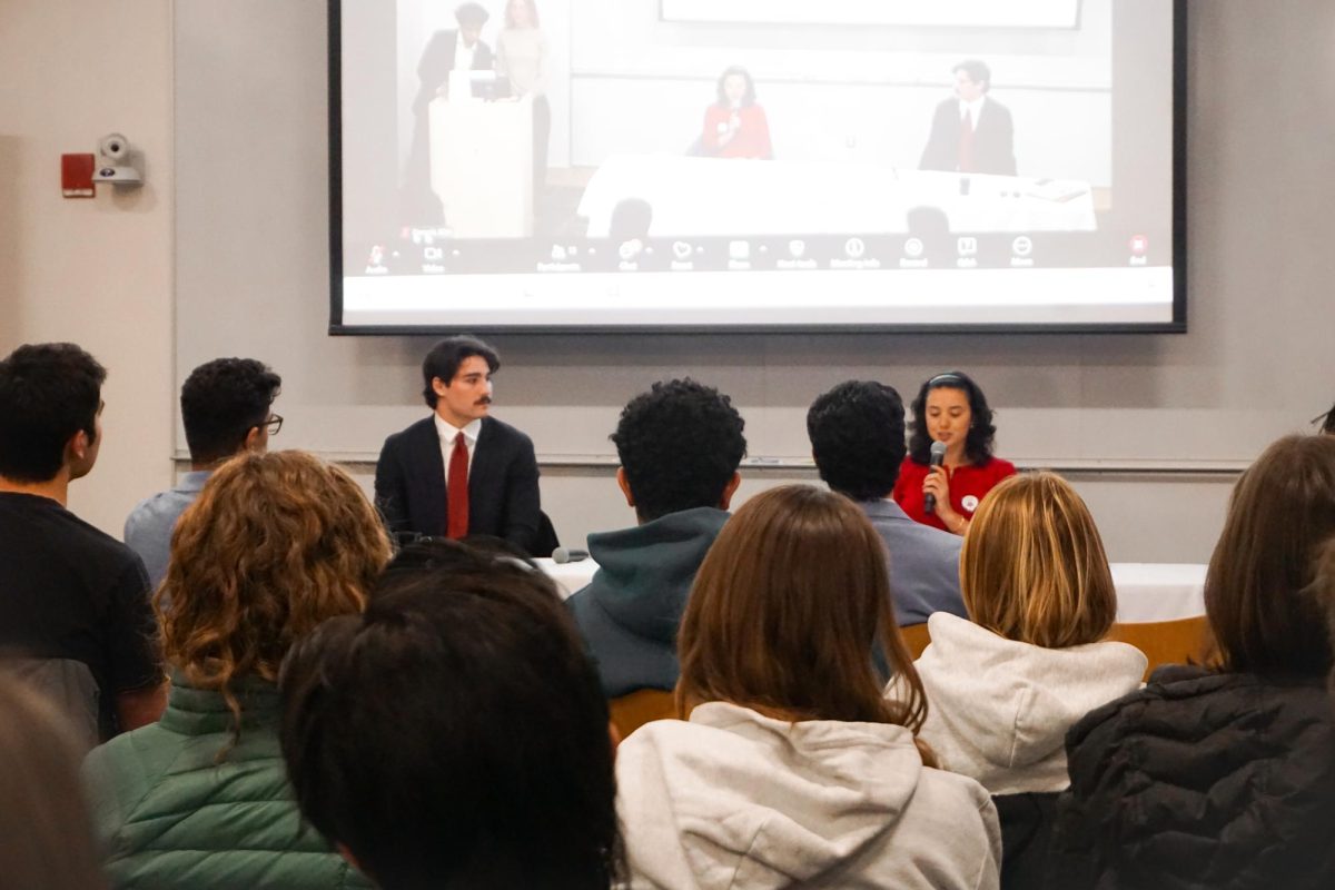 Students watch Miles Schmidt '27 and Ava Steinberger '27 debate on stage.