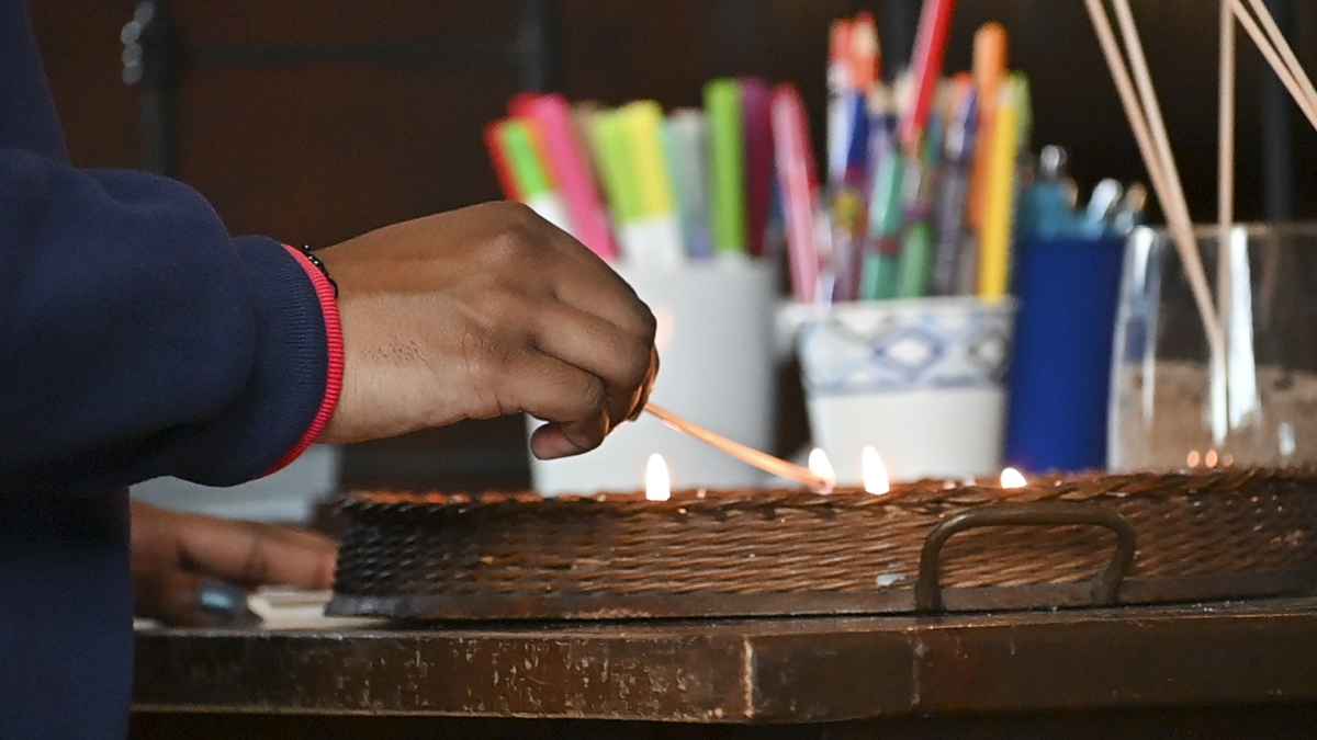 A Bates student lighting a candle during the Practicing Peace Event.