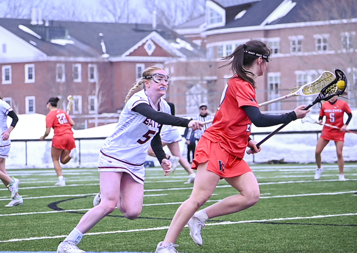 Laci Raveis '27 about to steal the ball from the opponent during the Bates Women's Lacrosse game versus Wesleyan.